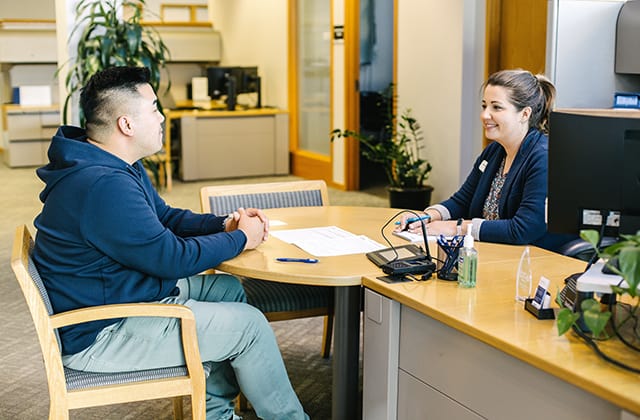 member at service desk with associate in sound credit union lobby