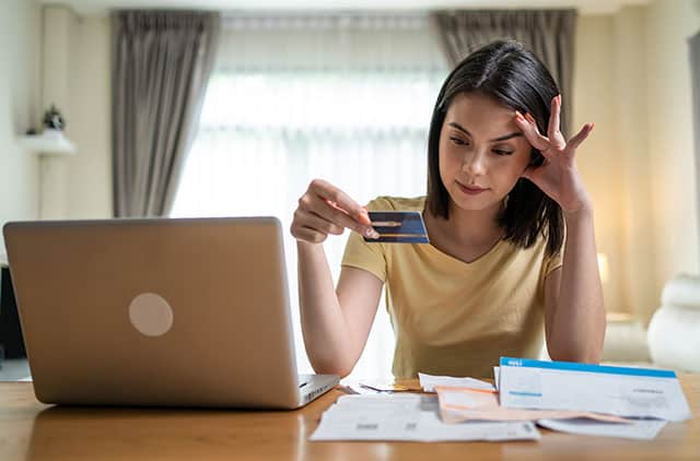 A woman looking distressed over bills.