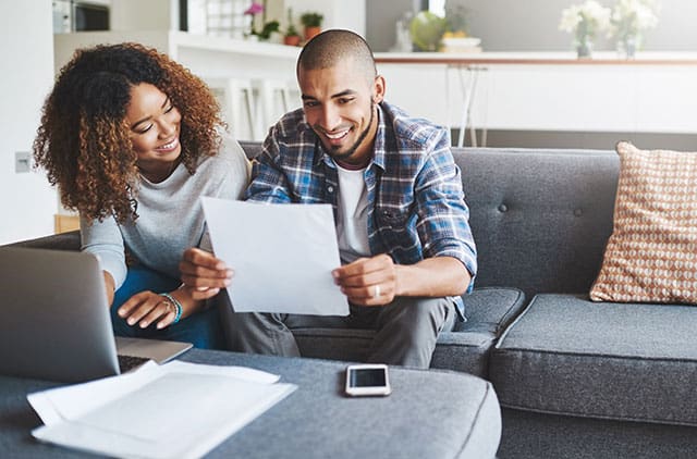 A couple looks over documents, while smiling.