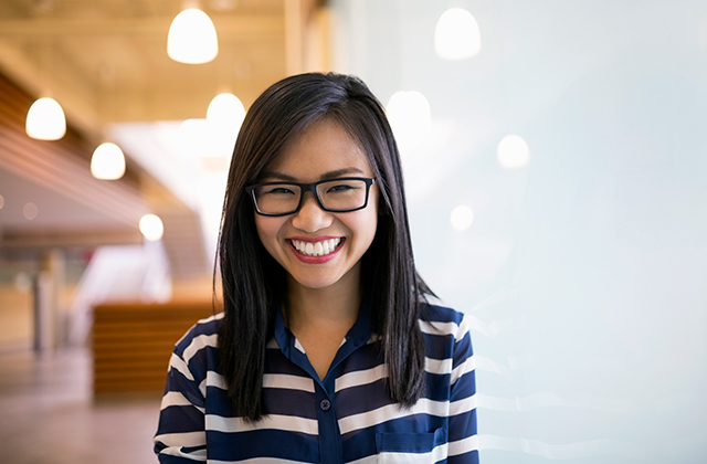 Cheerful lady with cute glasses in an office smiling at camera