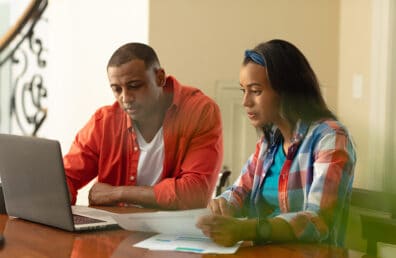 A couple looking at a laptop while planning their budget.