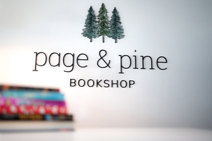 page & pine bookshop logo and stack of books on white counter.