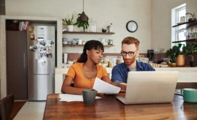 two people planning at table with papers in hand and laptop