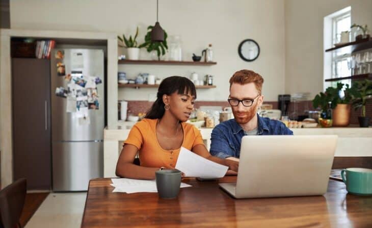 two people planning at table with papers in hand and laptop