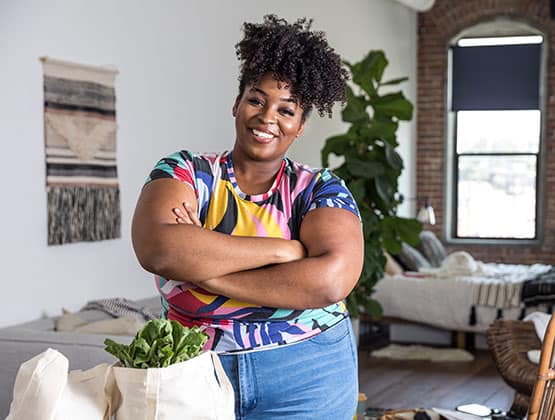 Woman smiling in her living room after bringing home groceries