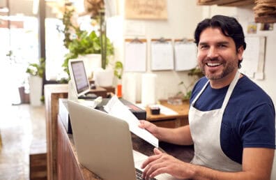 A plant shop owner smiling while working on a computer.