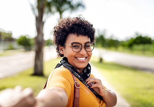 woman standing in a park taking a smiley selfie