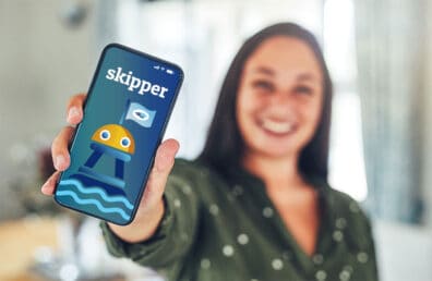young woman holding up an iphone with Sound's digital assistant, Skipper, on the call screen.