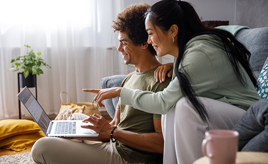 couple in living room shopping for a car on their laptop together