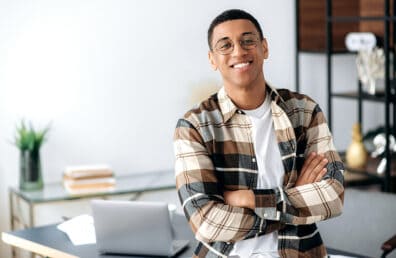 A young man smiling confidently while looking at the camera.