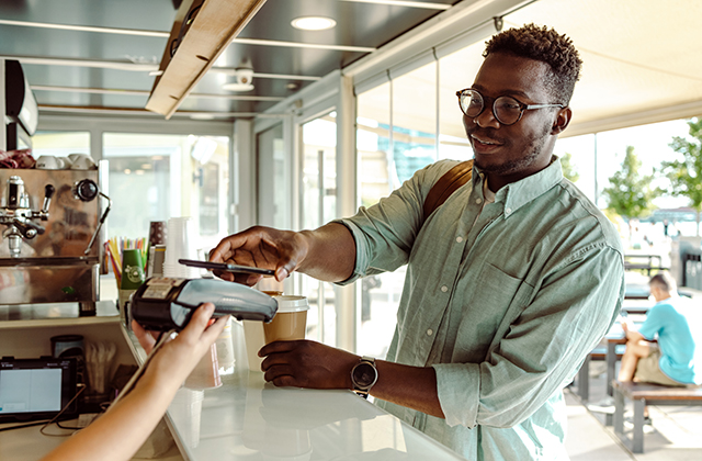 young man paying at the coffee shop with his smartphone