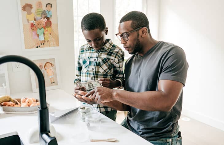 A father teaches his son about financial budgeting using cash.