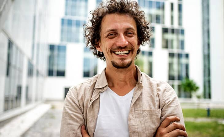 modern mid adult man outdoors standing with arms crossed and looking at camera