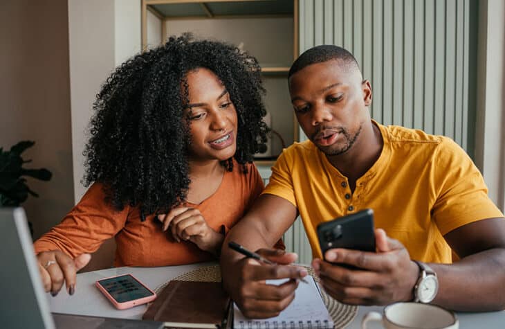A couple using a laptop and phone to review their finances.