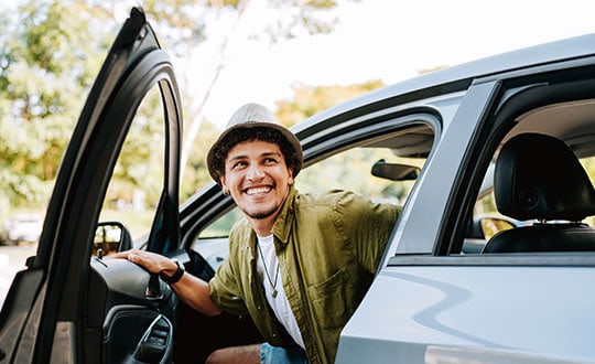 Young man traveling by car getting out of the car