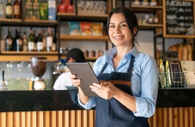 Latin American waitress working at a coffee shop using a digital tablet - food service concepts