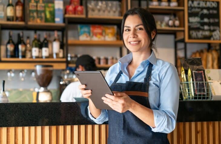 Latin American waitress working at a coffee shop using a digital tablet - food service concepts