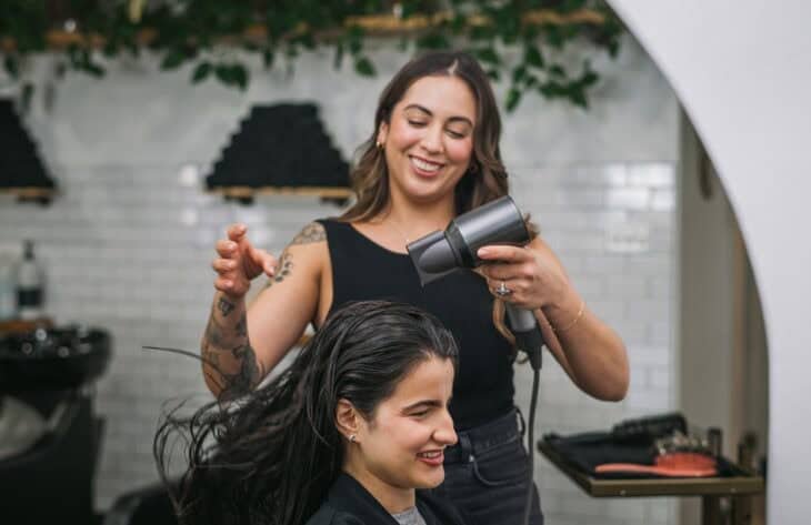 Female Stylist Blowing Out Woman's Hair at a Salon