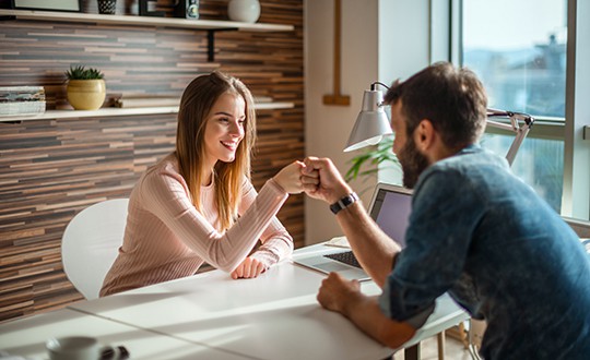 business partners fist bumping across desk