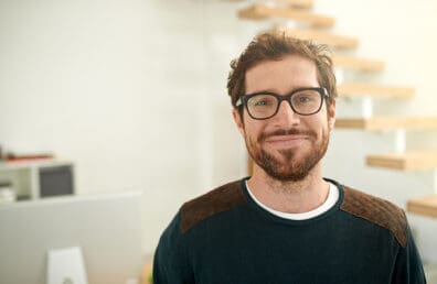 Young entreprenuer with glasses looking at camera in modern office