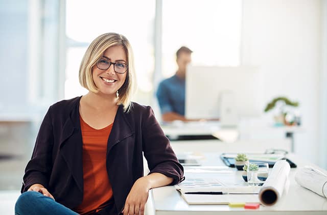 Happy professional with glasses smiling at camera from desk