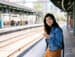 Student traveler on the go at a train station doing mobile banking with their smart phone