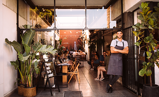 Young male business owner standing outside hipster urban café