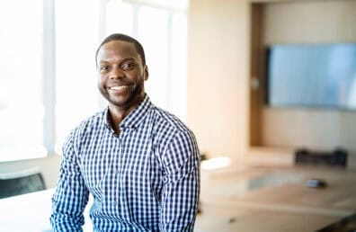 A man smiling at the camera in a meeting room.